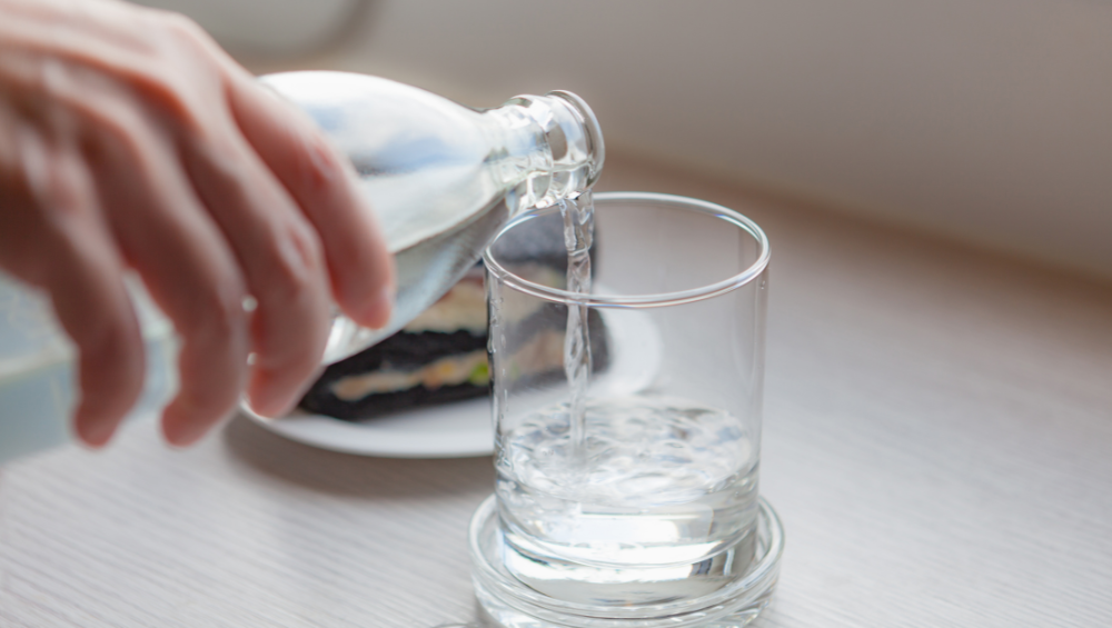 Como Ter Um Glow Up - Beba água e se alimente melhor - mulher colocando agua no copo para beber.
