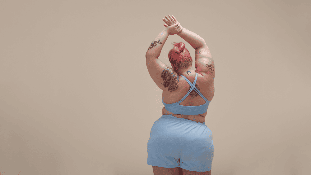Como Ter Um Glow Up - Mexa o corpo - mulher de costas com as mãos para cima em movimento de dança.