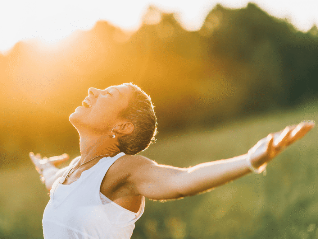 O que significa viver com propósito - Escute o que te dá energia O que significa viver com propósito - Escute o que te dá energia - foto de mulher com braços abertos no por do sol