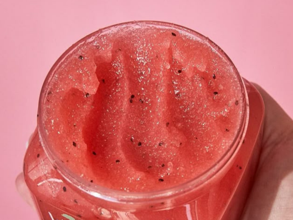 Banho Premium - esfoliação Corporal Renovando a Pele e a Alma - imagem com fundo rosa com um pote de esfoliante bem vivo de um vermelho com sementes.