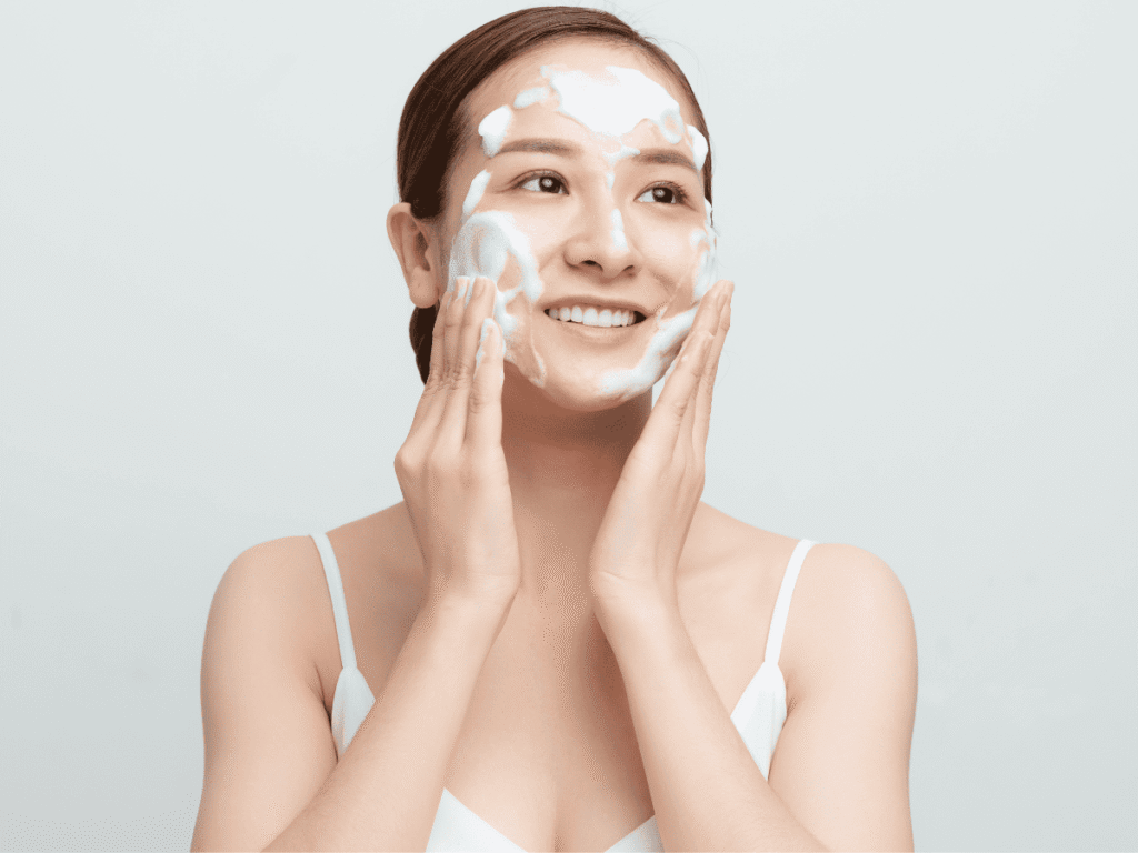 Como Começar a Cuidar de Si Mesma - Busque o Seu Glow Up Pessoal - imagem de mulher lavando o rosto e sorrindo