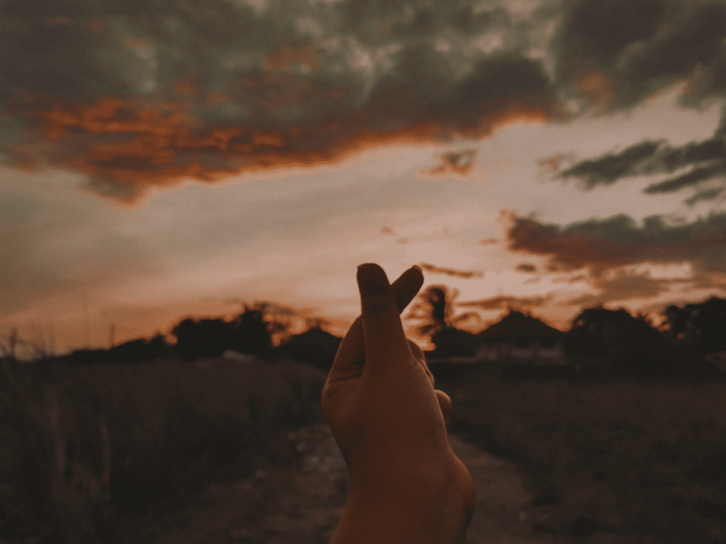Como Começar a Cuidar de Si Mesma - Conclusão O Momento de Começar a Sua Melhor Versão é AGORA!  - imagem de um por do sol e uma mão fazendo um coração coreano, representando sua nova e melhor versão